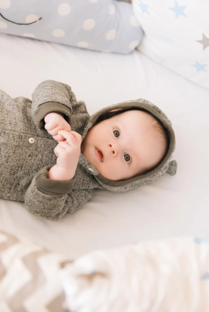 beau bebe nouveau ne couche dans un lit ovale avec de beaux pare chocs dans des tons gris bleus et blancs delicats
